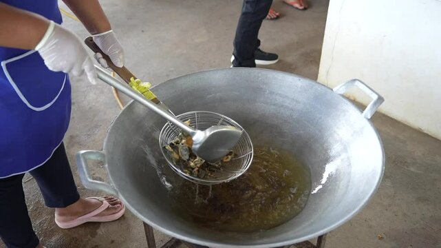 Traditional cooking method of frying frog skin in a pan with oil
