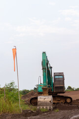Heavy excavator and windsock on muddy construction site
