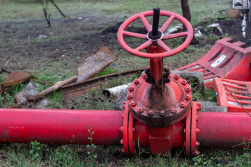 Large red industrial pipe with valve on rough terrain