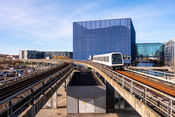 Metro train approaching station with modern office buildings in background, Havnestad, Copenhagen, Denmark, showcasing urban rail solutions