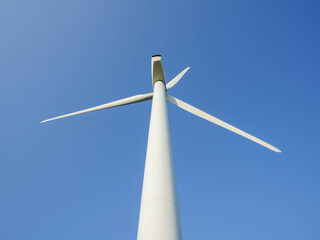 A wind turbine stands tall against a cloudless blue sky