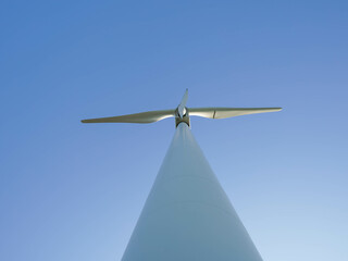 Bottom view of a modern wind turbine against a clear blue sky