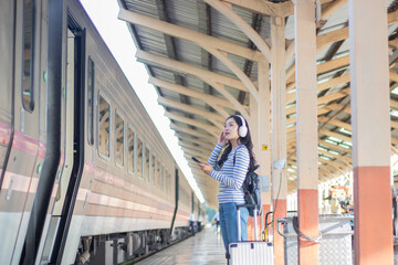 Young woman stands alone on a train platform, holding a smartphone and map, looking for direction—capturing a moment of travel, connection, and modern lifestyles.