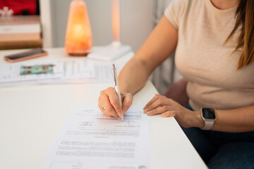 Woman signing business contract at home office desk