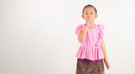 Portrait Thailand kid girl smiling traditional Thai dress costume making finger on lips mouth...