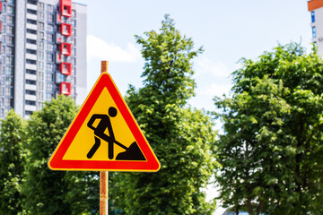 A yellow and red construction sign featuring a man on it for safety