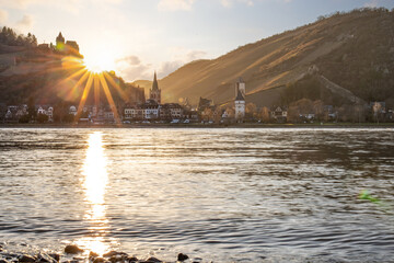 Sunset over hills by the river. The sun shines over hills and vineyards and is reflected in the...