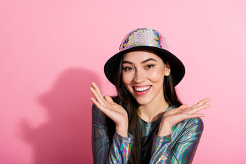 Radiant young woman in disco style attire smiling brightly against a colorful pink background showcasing cheerful and stylish lifestyle