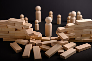 Wooden figures gather around scattered blocks, depicting a moment of disruption and the potential...