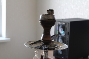 Close-up of a hookah bowl filled with flavored tobacco and topped with glowing hot charcoal. The...