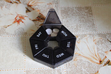 A seven-day pill organizer with labeled compartments for each day of the week. Commonly used for managing daily medication or supplements.