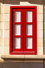 Obraz premium Bright red and white window shutters in stone building.