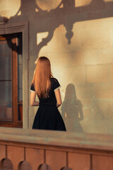 A young woman stands with her back to the camera, casting a shadow on a wall. A symbolic image reflecting inner self, hidden fears, and moments of doubt.