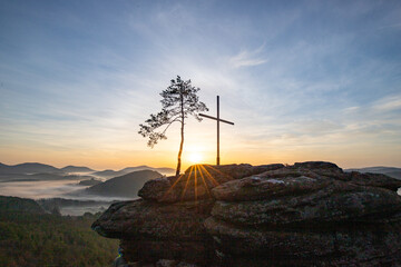 Sunrise over a mountain landscape. Rising sun behind a sandstone cliff in the forest. Fog forms in...