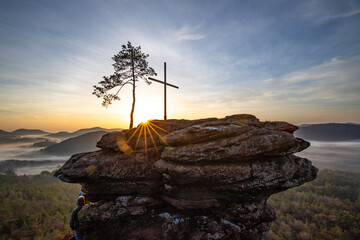 Sunrise over a mountain landscape. Rising sun behind a sandstone cliff in the forest. Fog forms in...