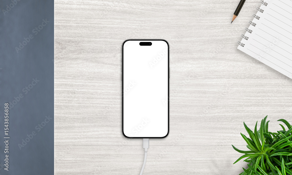 Aufkleber Top view of smartphone on charger with blank screen, placed on desk with notebook and plant. Ideal for productivity and app mockups