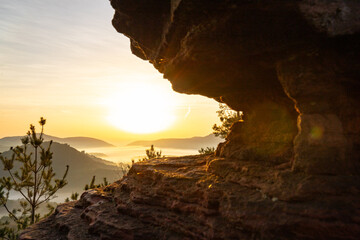 Sunrise over a mountain landscape. Rising sun behind a sandstone cliff in the forest. Fog forms in...