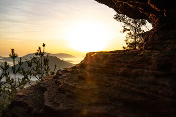 Sunrise over a mountain landscape. Rising sun behind a sandstone cliff in the forest. Fog forms in...