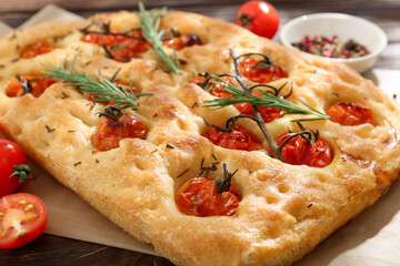 Delicious focaccia with tomatoes and spices on table, closeup