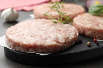 Fresh raw patties for burger and spices on grey table, closeup