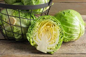 Fresh cabbages and basket on wooden table, closeup