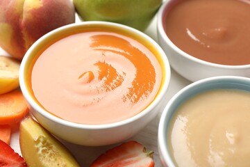 Baby food. Tasty puree in bowls and different ingredients on table, closeup