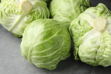 Fresh green cabbages on grey table, closeup