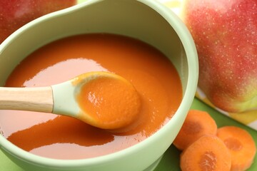 Baby food. Tasty puree in bowl and ingredients on green background, closeup
