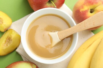 Baby food. Tasty puree in bowl and ingredients on green background, flat lay