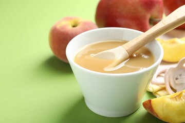 Baby food. Tasty puree in bowl and ingredients on green background, closeup. Space for text