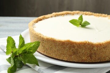 One tasty cheesecake with mint on grey table against brown background, closeup