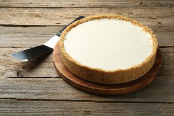 One tasty cheesecake and server on wooden table, closeup