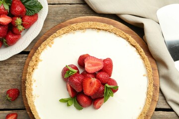 Tasty cheesecake with strawberries and mint on wooden table, flat lay