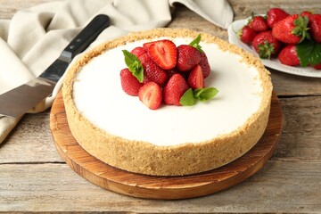 Tasty cheesecake with strawberries and mint on wooden table, closeup