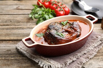 Traditional ossobuco dish with beef steak and sauce served on wooden table, closeup