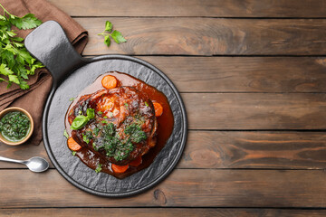 Traditional ossobuco dish with beef steak and sauce served on wooden table, flat lay. Space for text