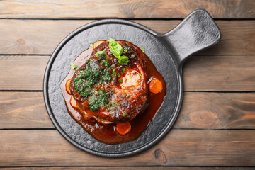 Traditional ossobuco dish with beef steak and sauce served on wooden table, top view