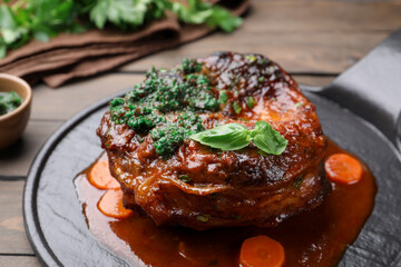 Traditional ossobuco dish with beef steak and sauce served on wooden table, closeup