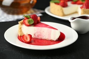 Piece of tasty cheesecake with strawberries, sauce and mint on black table, closeup