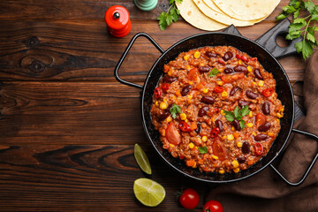 Tasty chili con carne in baking dish and flatbread on wooden table, flat lay. Space for text