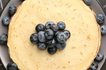 Delicious crepes with blueberries on table, top view