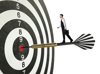 Goal achievement, business success and targeting. Businessman walking on dart sticking in center of...