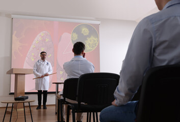 Healthcare professional giving lecture about lung diseases in conference room using video...