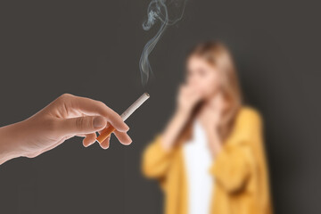 Passive smoking. Girl coughing because of woman smoking nearby on grey background. Selective focus
