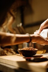 A pastry chef carefully adds colorful ingredients to a bowl while preparing cozonac decorations...