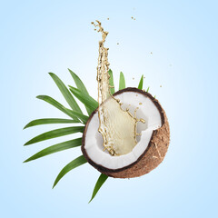 Coconut oil splashing out of nut on light blue background
