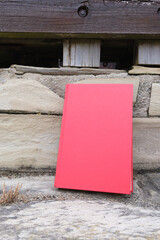 Red book leaning on a stone wall outdoors with copy space.