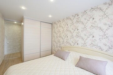 Cozy bedroom with a double bed, floral wallpaper, built-in wardrobe, and soft lighting