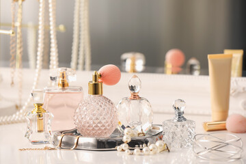 Bottles of different perfumes and accessories on dressing table indoors