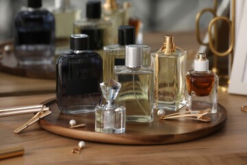 Bottles of different perfumes and accessories on wooden table, closeup